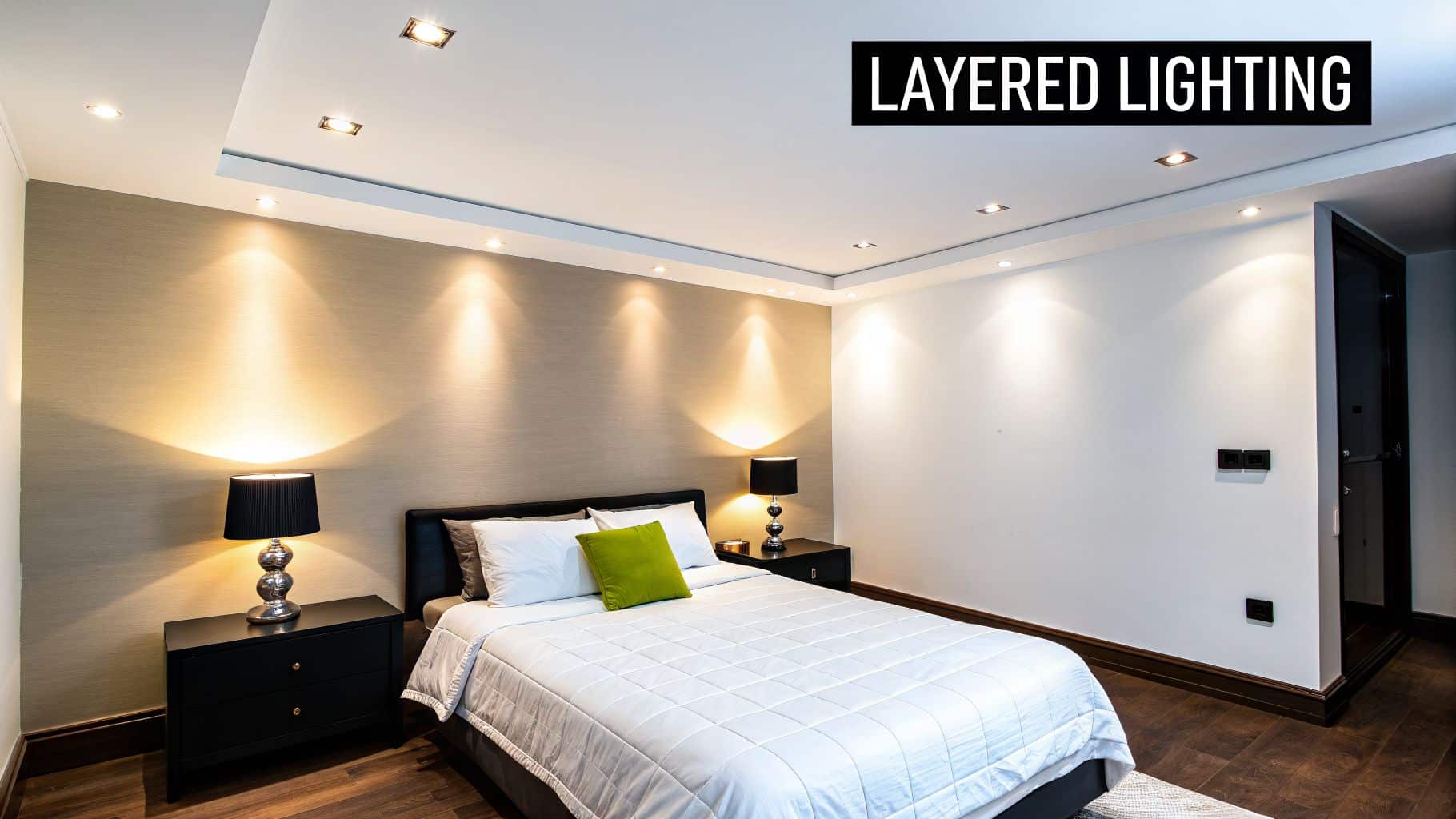 A modern bedroom showcasing effective layered lighting with recessed lights and accent wall lighting.