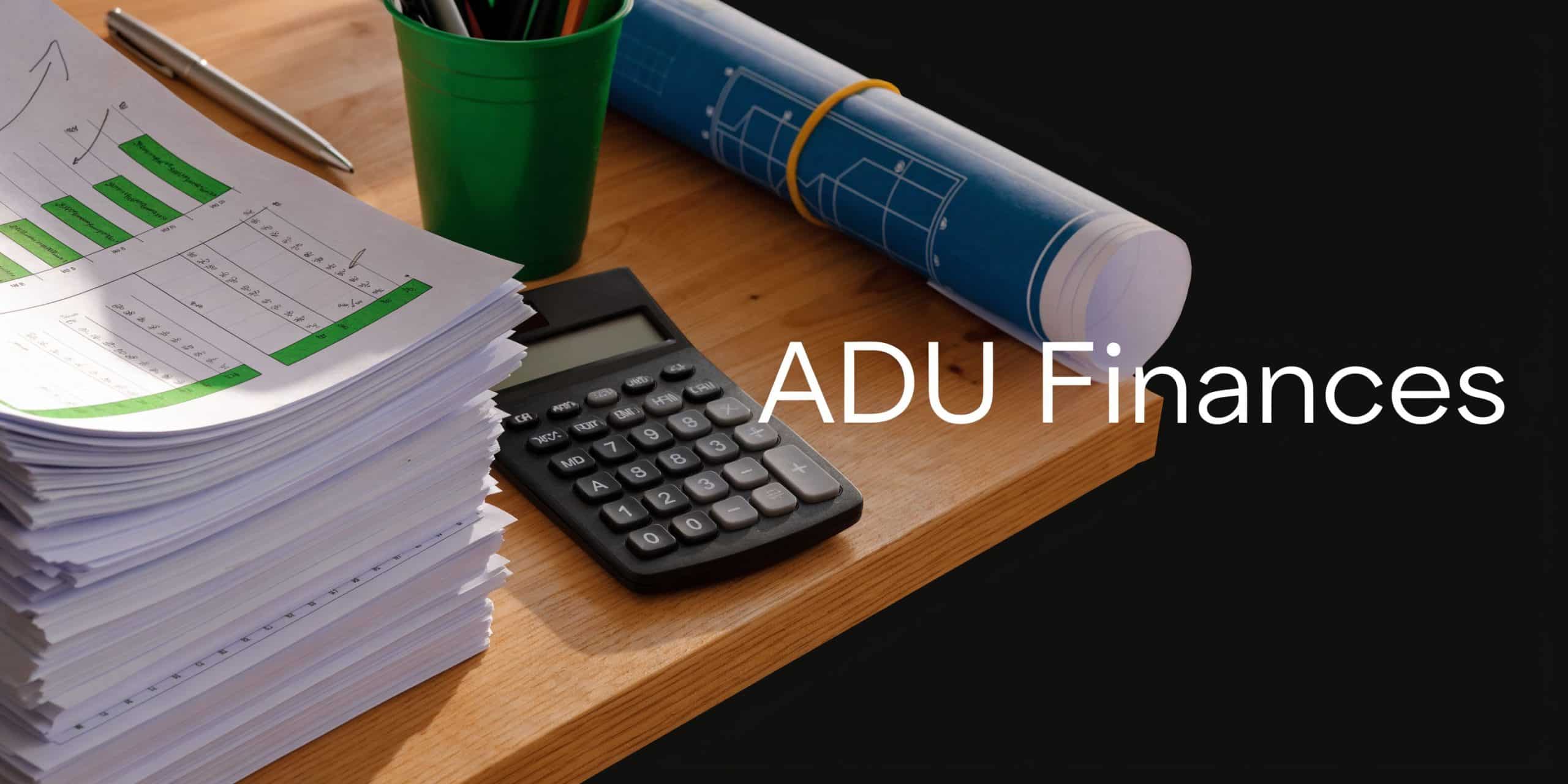 A workspace featuring a stack of financial documents, a calculator, a pen, and blueprints on a wooden desk.